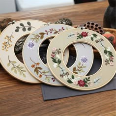 four wooden hoops with flowers painted on them sitting on a table next to other items