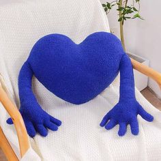 a blue heart shaped stuffed animal sitting on top of a white chair next to a potted plant