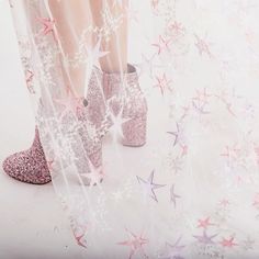 a woman's legs with pink glitter shoes and stars on the ground behind her