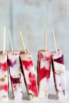 four popsicles with red and white toppings on sticks