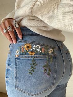 a woman is showing off her jeans with flowers on them