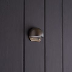 a door handle on the side of a dark colored wooden door with vertical panels and metal hardware