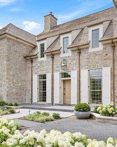 a large stone house with white flowers in the front yard