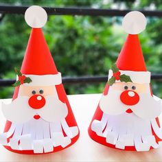 two red and white paper santa hats sitting on top of a table