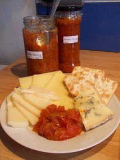 a white plate topped with lots of cheese and crackers next to jars of sauce