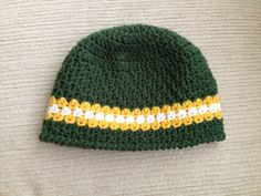 a green and yellow knitted hat laying on top of a bed