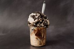 an ice cream sundae with oreo cookies on top in a glass cup, against a dark background