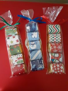 three wrapped presents are sitting on a red surface