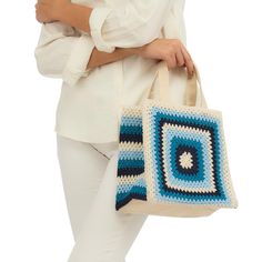 a woman carrying a crocheted bag with blue and white squares