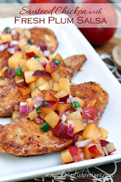 grilled chicken with fresh plum salsa on a white platter next to an apple