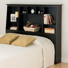 a black bookcase headboard with two pillows on top of it and bookshelves above the bed