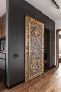 an ornate wooden door in the middle of a room with dark walls and wood floors