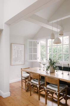 a dining room table with four chairs and a potted plant in the center on top