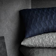 three pillows stacked on top of each other in front of a gray wall and floor