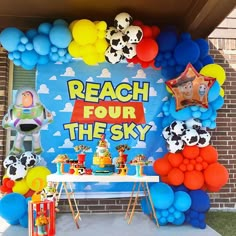 a table topped with balloons next to a sign that says reach four the sky on it