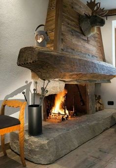 the fireplace is made out of logs and has a moose head on it's mantle