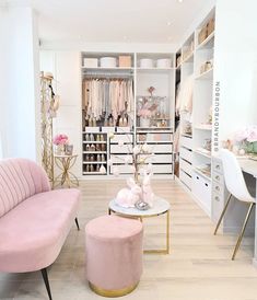 a pink couch sitting in front of a white closet filled with lots of clothes and accessories