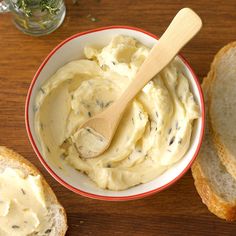 a wooden spoon in a bowl filled with mashed potatoes and bread on a table