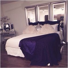 a large bed with pillows and blankets on it in front of two mirrored mirrors above it