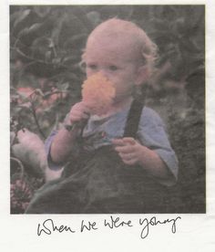 a young child eating something while sitting on the ground