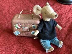 a toy mouse is sitting next to a suitcase