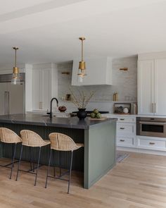 a large kitchen with an island and three bar stools in front of the sink