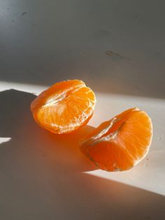 two peeled oranges sitting on top of a white counter next to a window sill