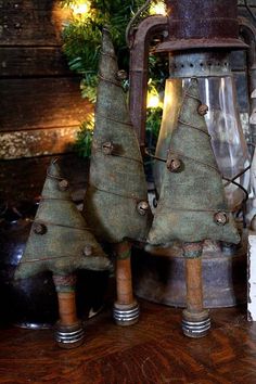 three small christmas trees sitting on top of a wooden table next to a light fixture