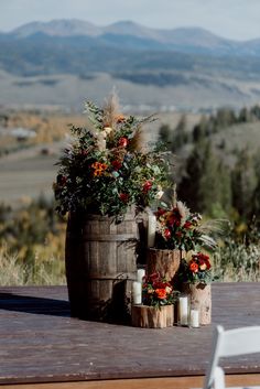 a wooden barrel with flowers and candles sitting on top of it next to a white chair