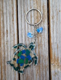 a sea turtle keychain is shown on a wooden surface with blue and green glass beads