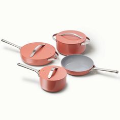 three pots and pans with lids on a white background, one has a spoon in it