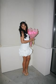 a woman in a white dress is holding a pink bouquet and posing for the camera