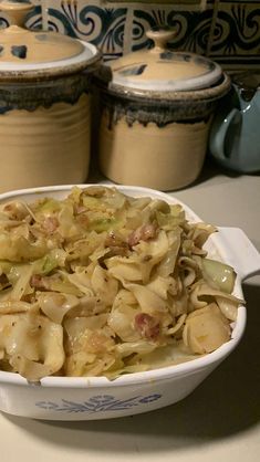 a casserole dish filled with cabbage and meat in front of two canisters