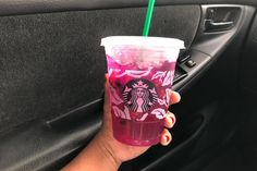 a person holding a starbucks cup in their hand while sitting in the passenger seat of a car