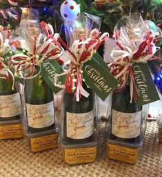 four bottles of wine with candy canes in them on a table next to a christmas tree