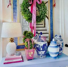 a table topped with vases and a wreath on top of a dresser next to a mirror