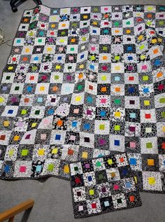 a quilt is laying on the floor next to a chair