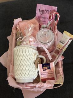 a pink gift basket with coffee, candy and other items in it on a table