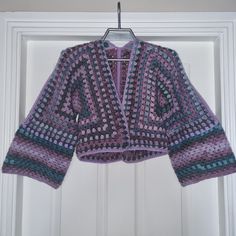 a crocheted jacket hanging on a white door