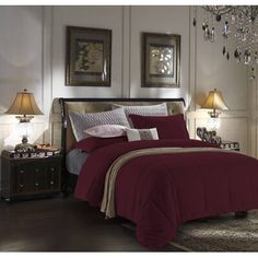 a bed room with a neatly made bed and two chandelier lamps on the wall