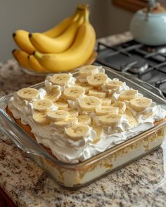 bananas and whipped cream in a glass dish on top of a counter next to a stove