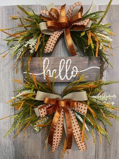 a wreath with the word hello written on it and two orange bows hanging from it