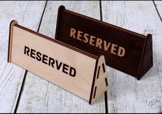 two wooden signs sitting on top of a white wood floor with words reserved and reserved