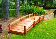 a wooden bridge in the middle of a grassy area next to some trees and plants