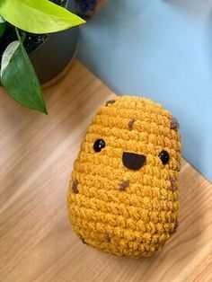 a crocheted stuffed animal sitting on top of a wooden table next to a potted plant