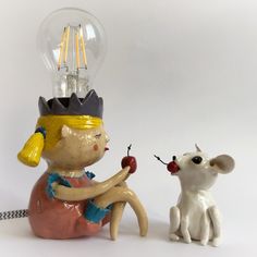 a ceramic figurine sitting next to a light bulb and a small white dog