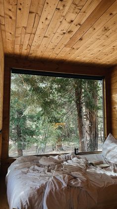 a bed sitting under a window next to a forest