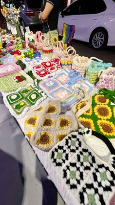 a table that has some knitted items on it and people standing around the table