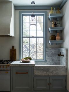 a kitchen with marble counter tops and open shelves on the wall, next to a window