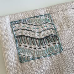 a piece of cloth has been stitched with blue thread and is sitting on a table